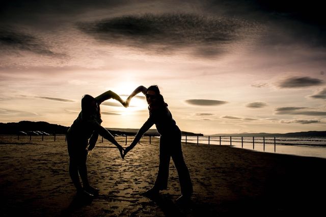 Silhouettes shaping a heart with their arms 