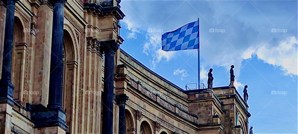 High above on the roof of the “Maximilianeum” in “Munich” the blue & white flag of “Bavaria” waves gently in the wind. This palatial structure has been the seat of the “Bavarian State Parliament”, the “Landtag” since 1949. 2024. Hypnotic Productions