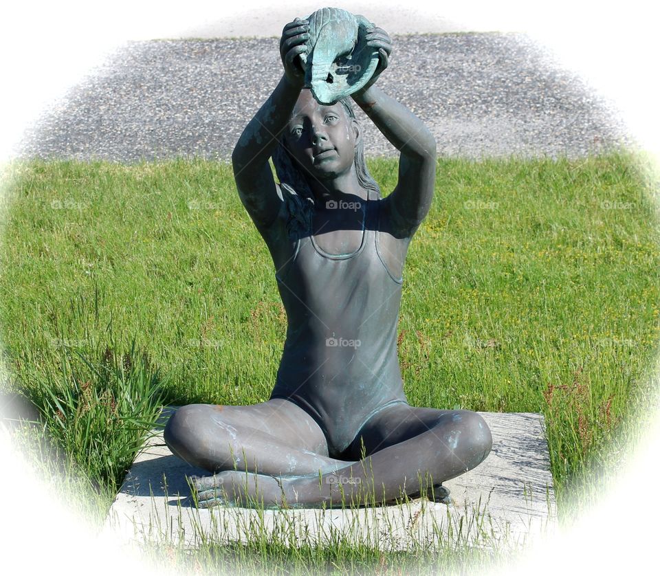 Bronze statue of young girl with a conch seashell