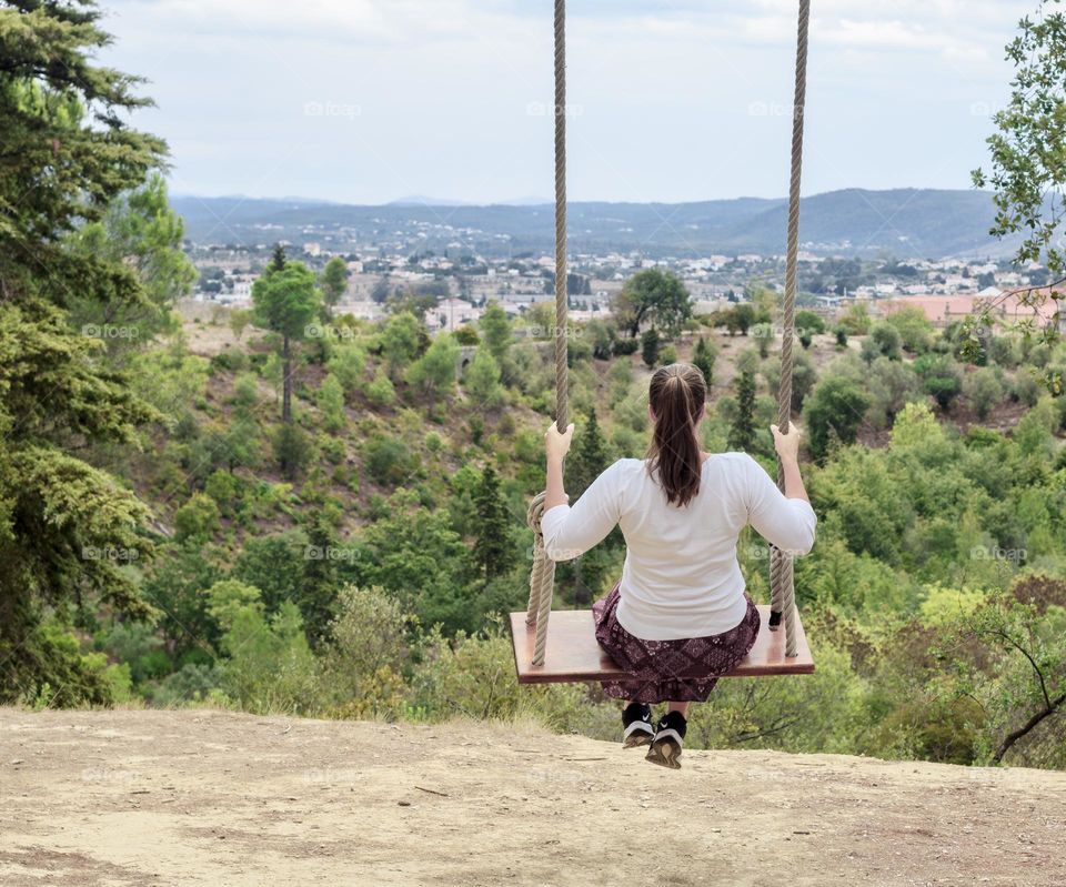A woman relaxes on a large swing enjoying the landscape 
