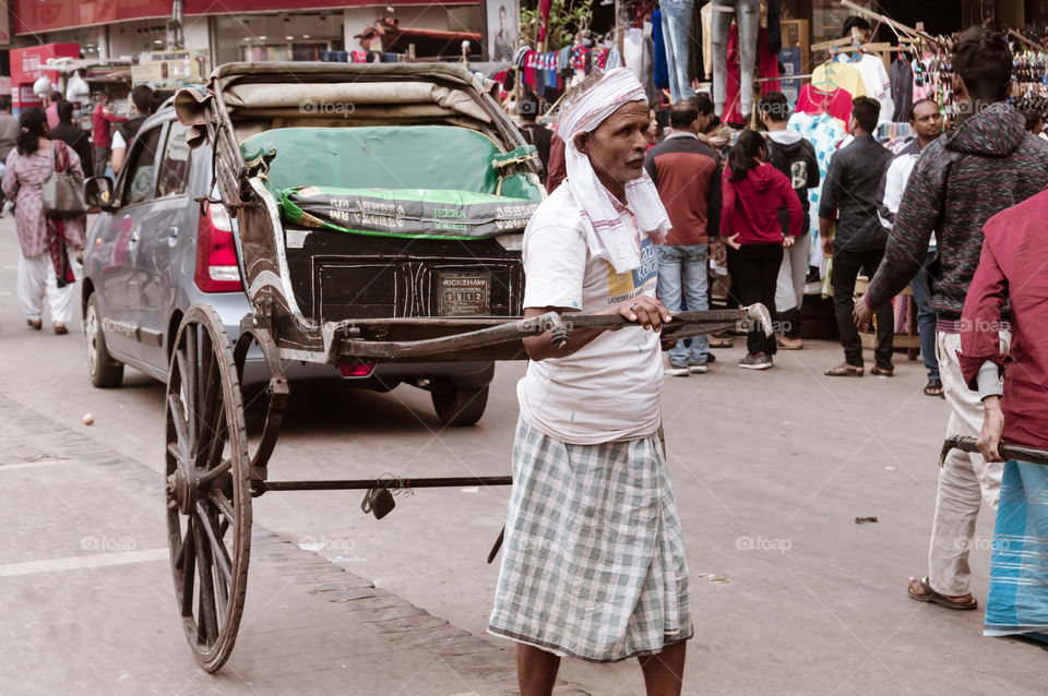 Kolkata, India 1 May, 2019 – A traditional tanga-wala rickshaw puller (human-drawn carriage driver) in city street of Kolkata at noon in summer months and not getting first passenger ride of the day.