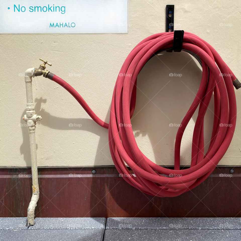 No smoking sign next to a red fire hose in Hawaii 