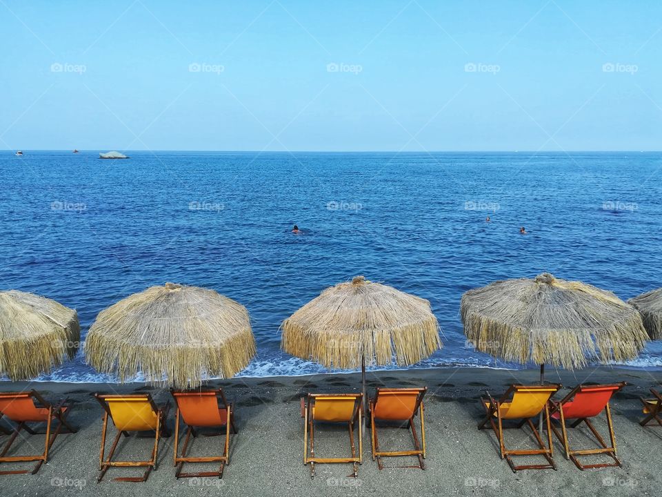 Beach umbrellas and deck chairs facing the sea