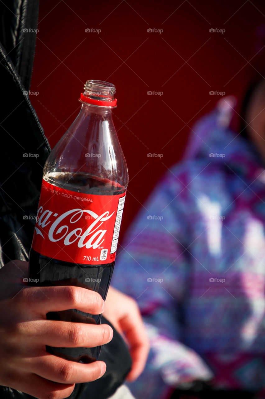 Open bottle of a Coca-Cola in a man's hand