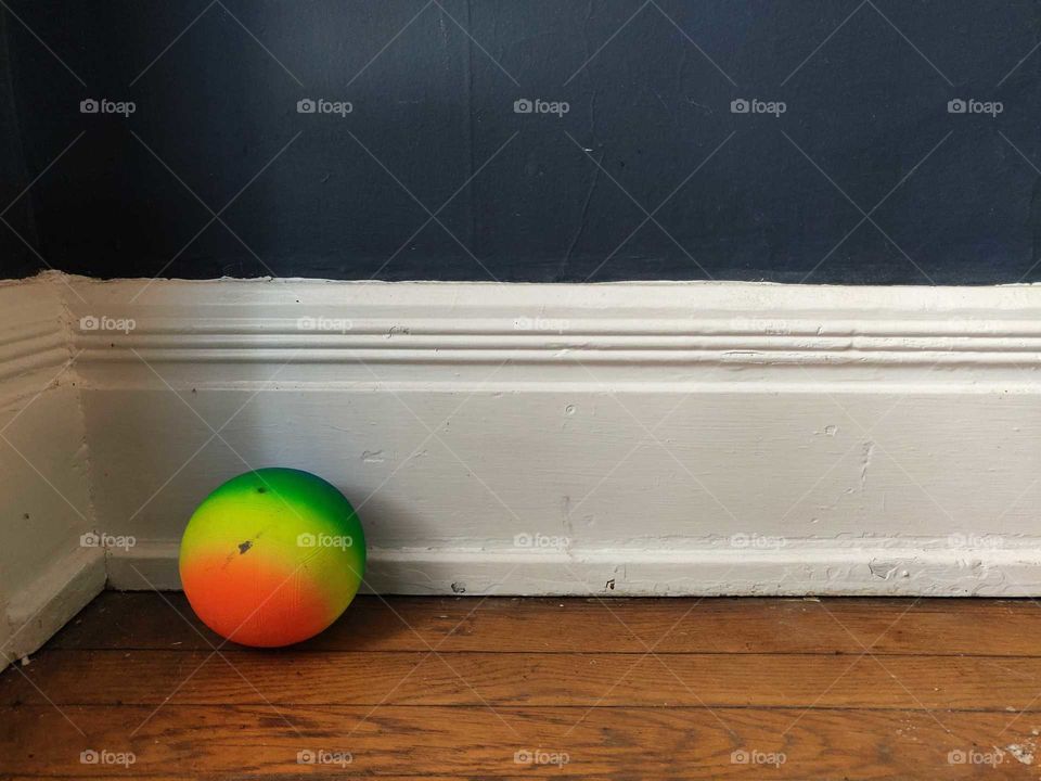 Neon rainbow ball, in the corner by the wall.