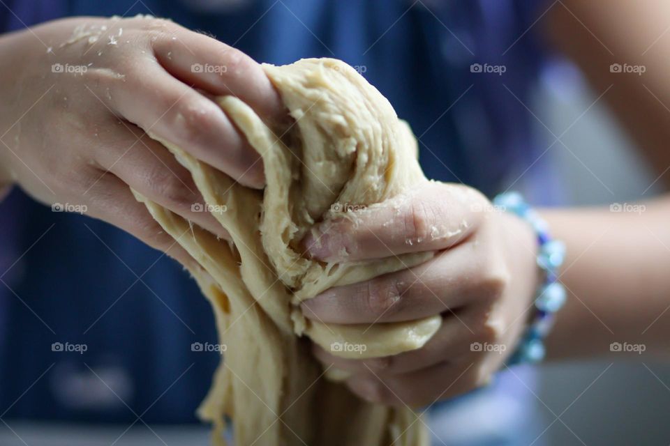 Cute girl's hands are mixing bread dough