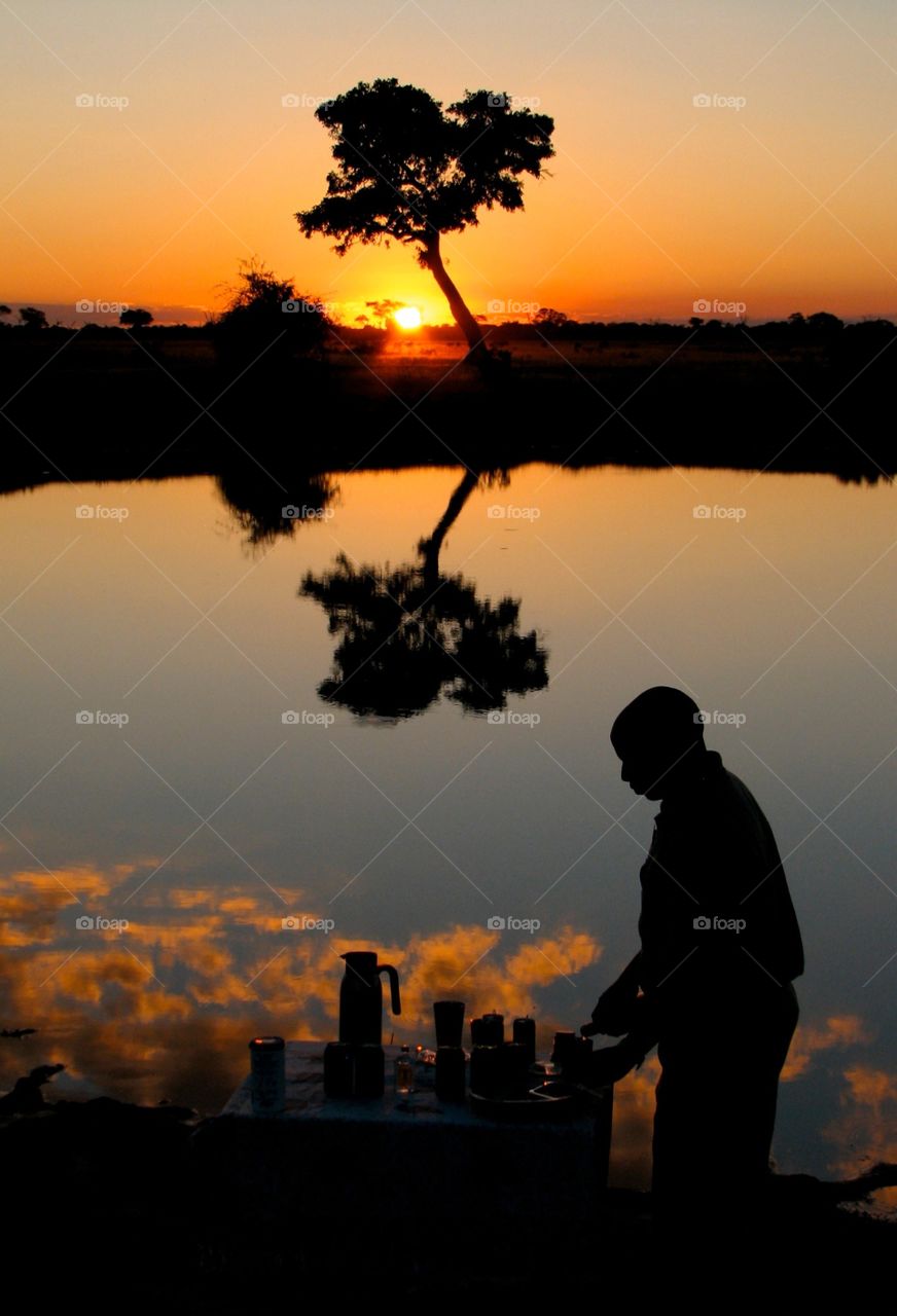 Sundowner in Botswana. Our guide sets up snacks and drinks while the sun sets on safari in Botwana.  This is known as a 'sundowner'.