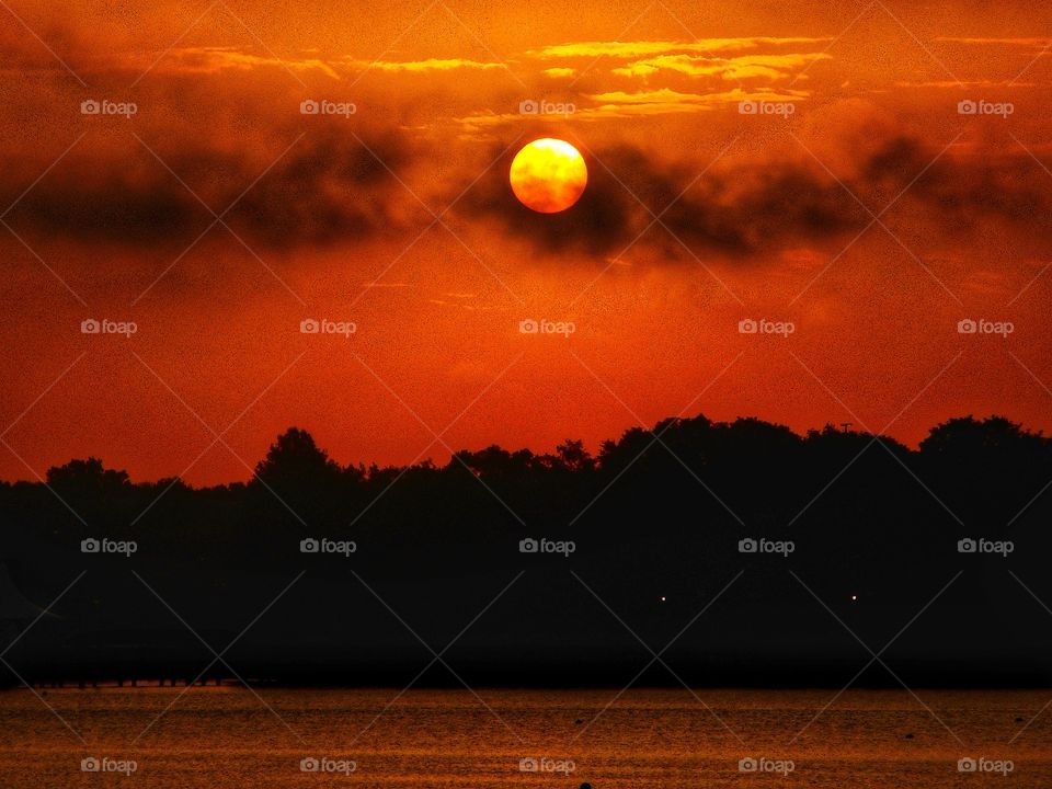 A beautiful golden orange sunrise above the lake at Cranes Roost Park in Altamonte Springs, Florida.