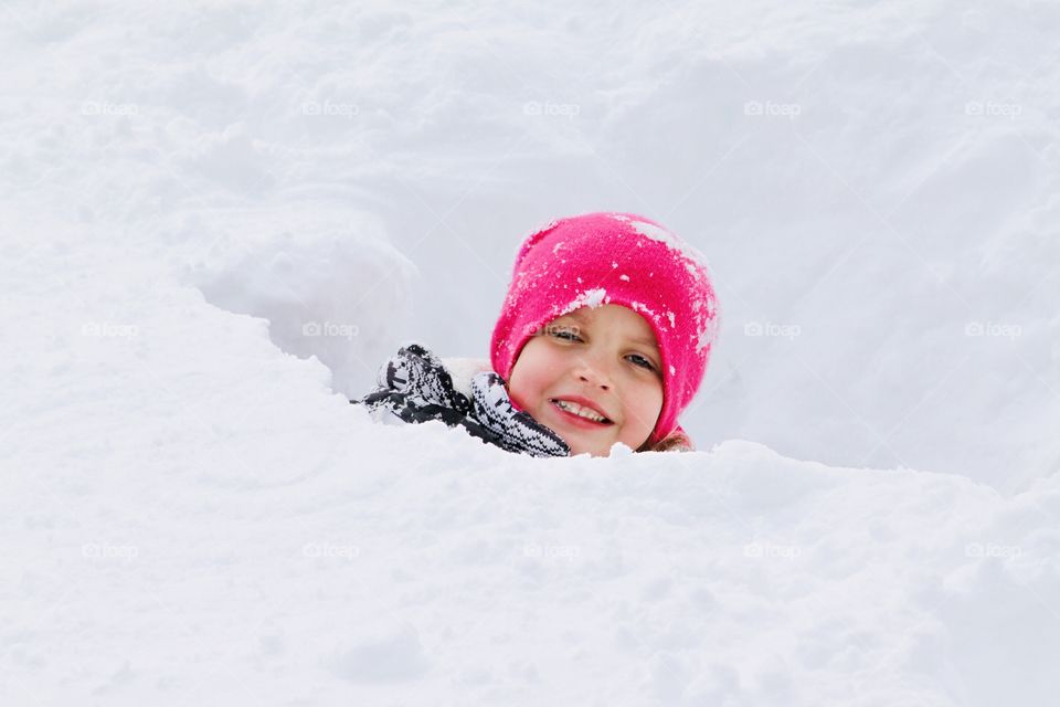 Darling little girl with bright pink stocking hat on sticking her head out of a snow fort is a sure sign of winter! 
