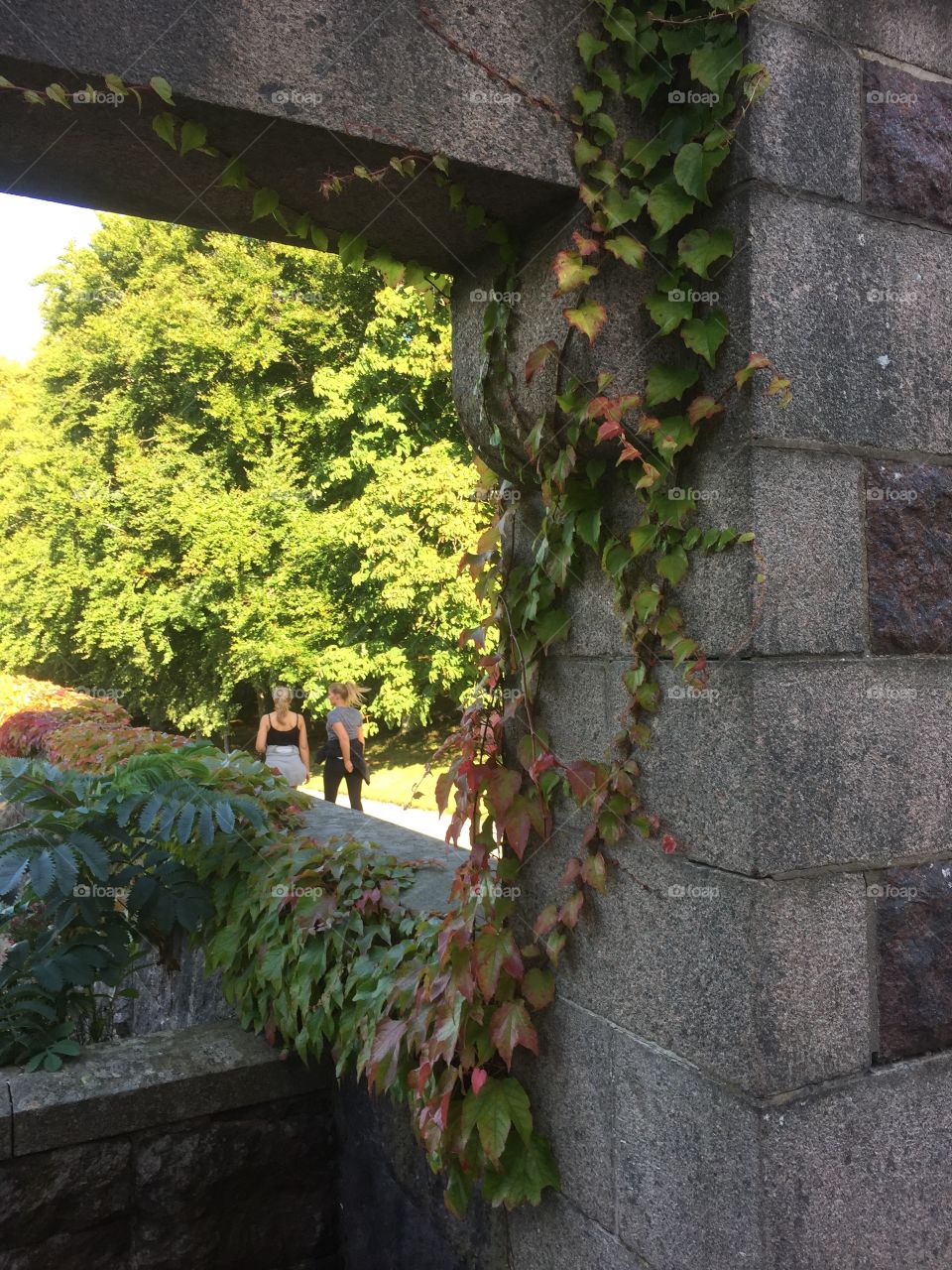 Two girls walking seen through a hole