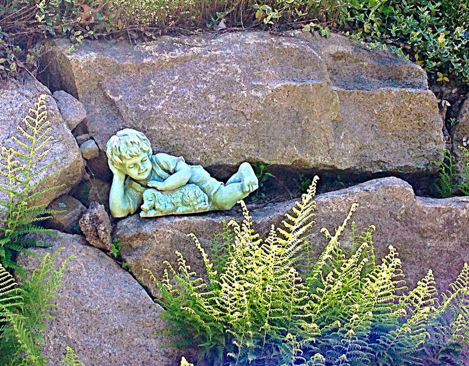 Boy sculpture in rock garden 