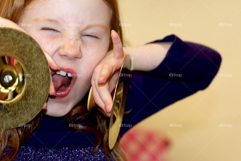 Female child having fun with a pair of cymbals.