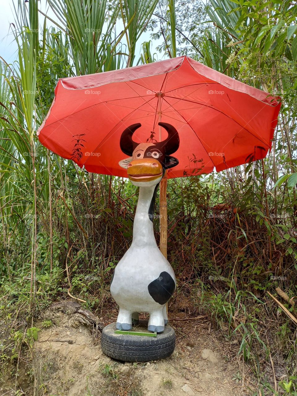 painted cement cow with umbrella