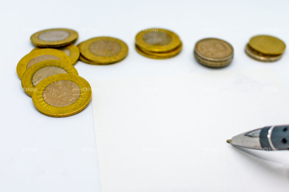 financial planning with coins and a pen isolated on a white background. Selected focus, narrow depth of field. Calculation of financial growth and investment concept