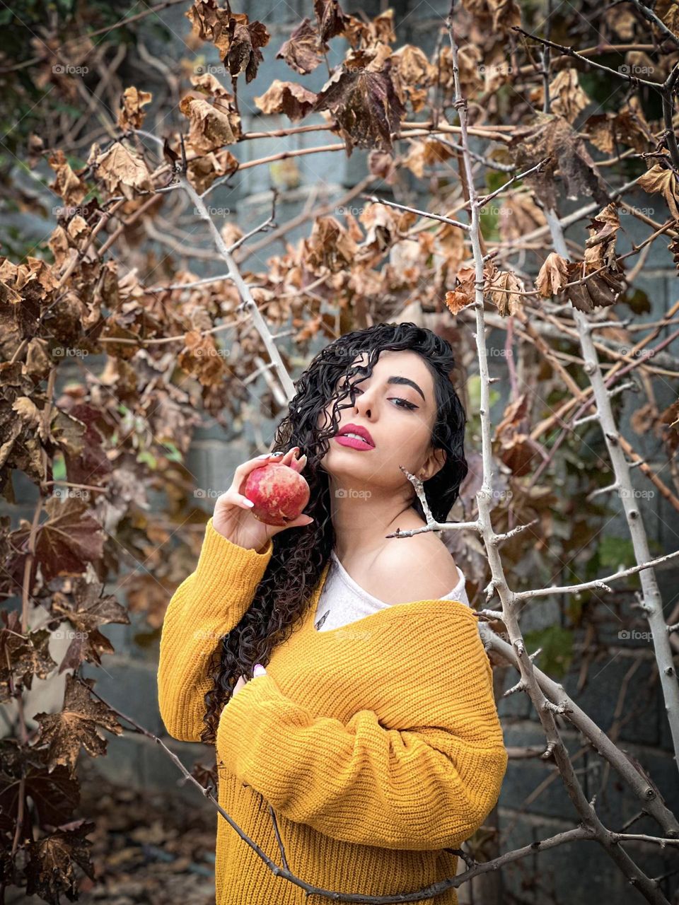Curly haired girl with pomegranate in autumn weather