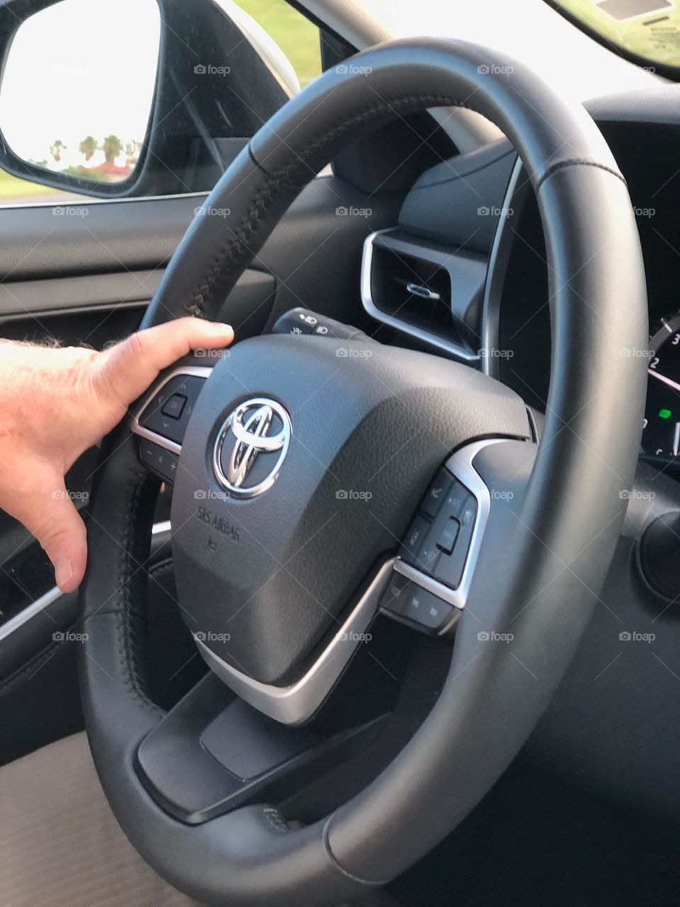Driving a car closeup of man’s left hand on steering wheel 