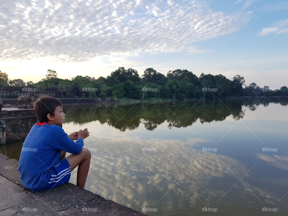 A boy is enjoying sunrise at angkor wat lake at siem reap cambodia.