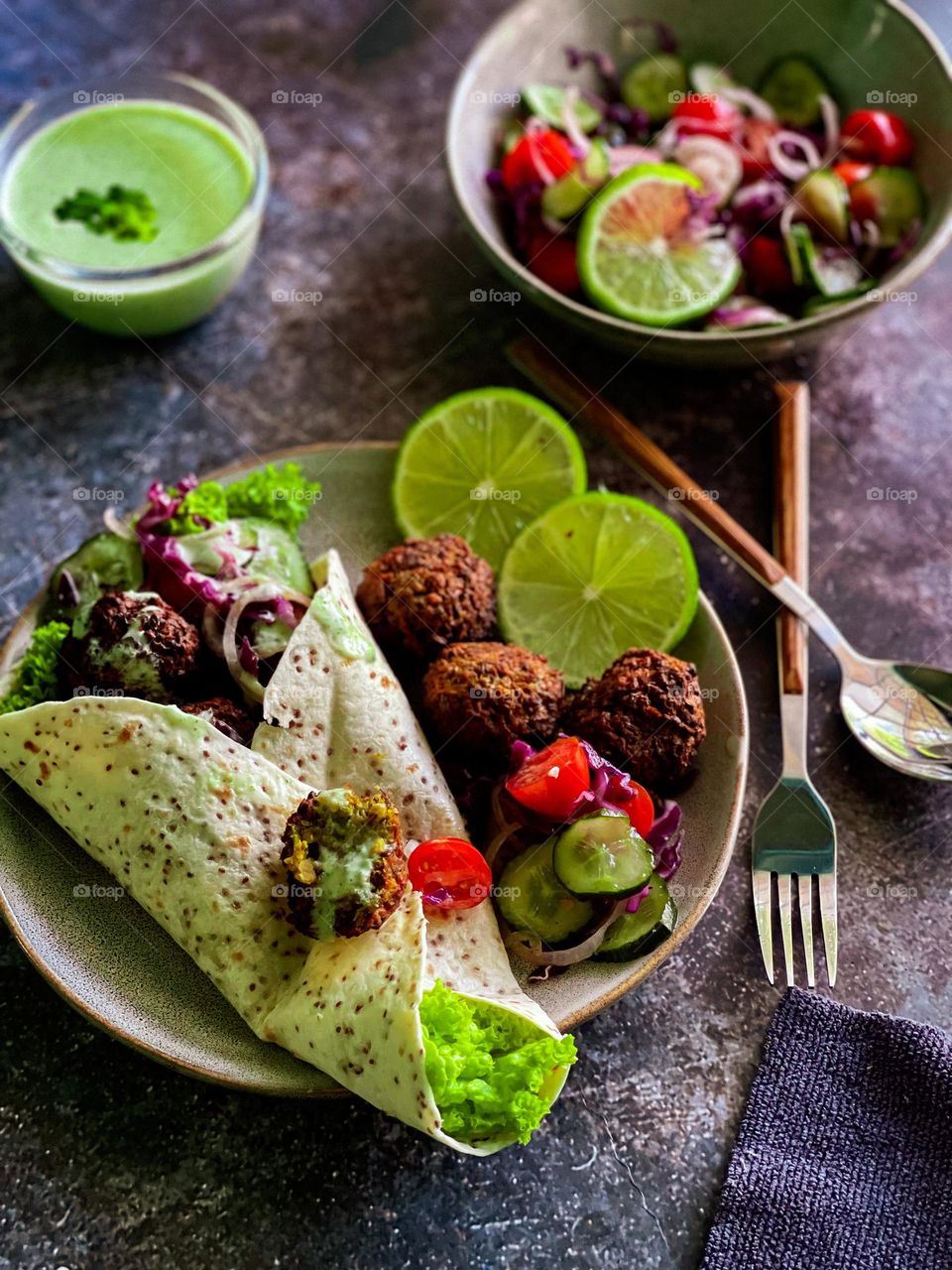 Fresh homemade falafel in wraps with some slices of lime on a plate. 