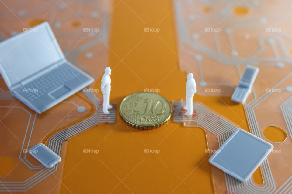 Man figurines and coin on printed circuit representing transaction of money