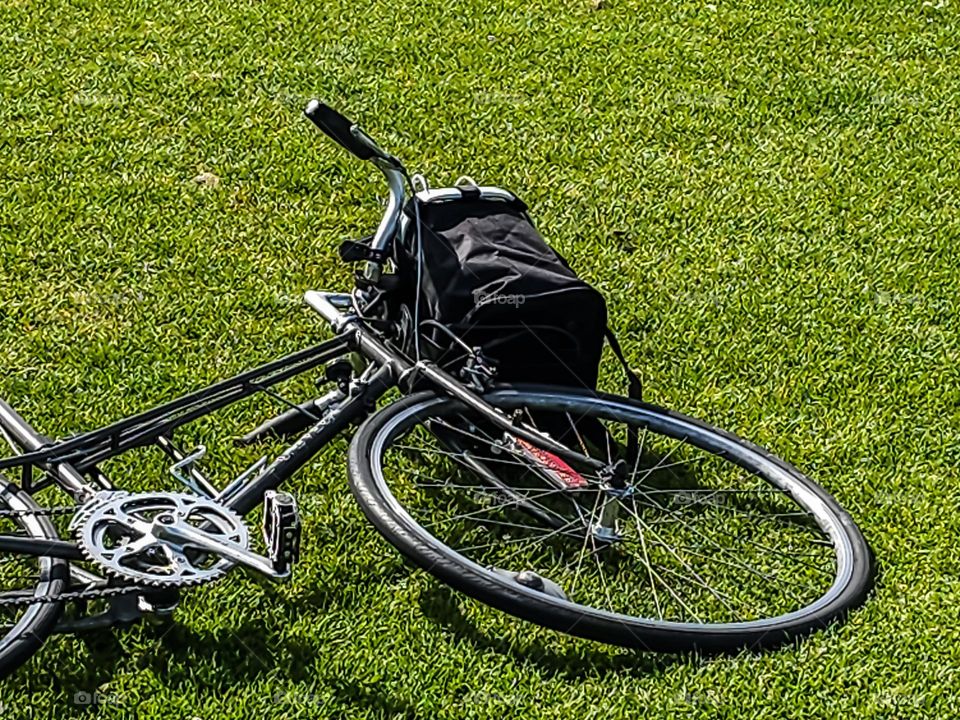 Black Bicycle lying in the grass after a long ride on a warm sunny spring afternoon 