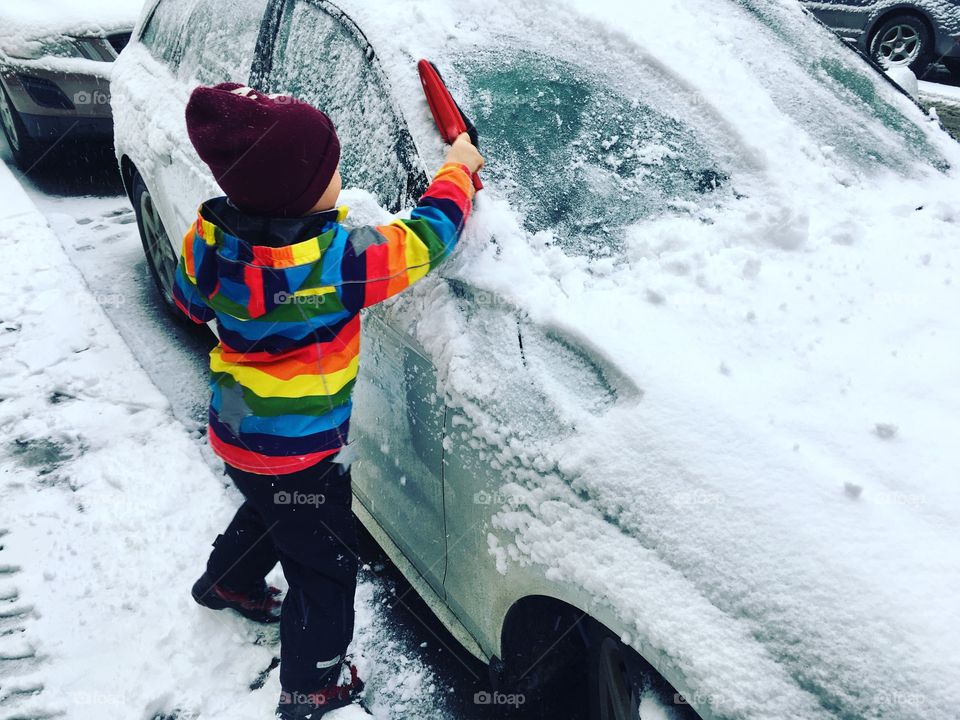 Kid brushing snow from car