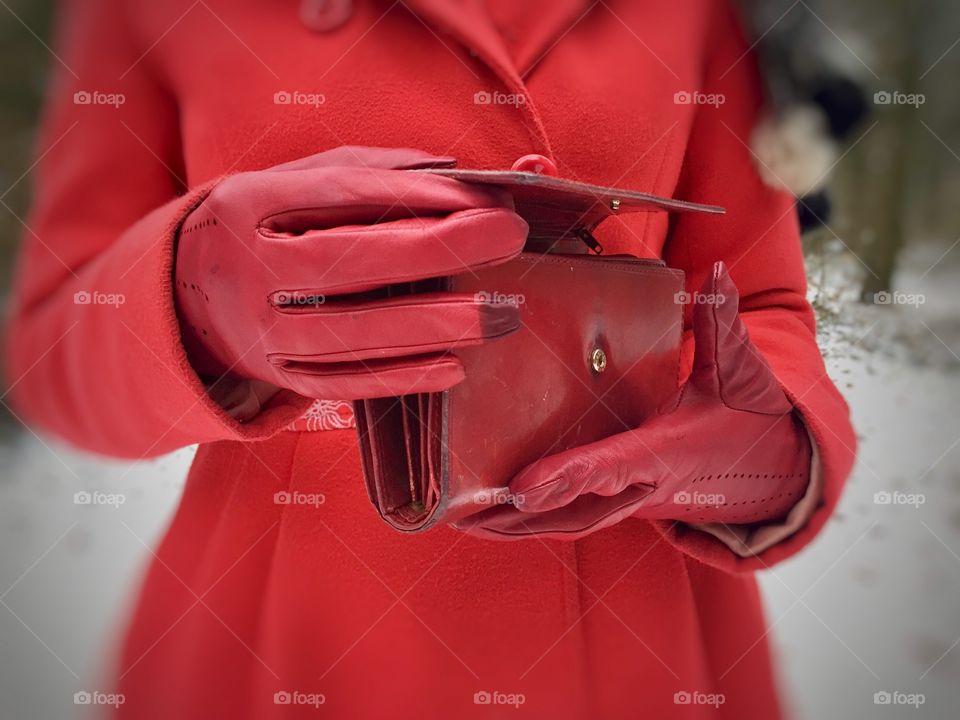 Woman with red jacket wearing red leather gloves holding a red matching wallet