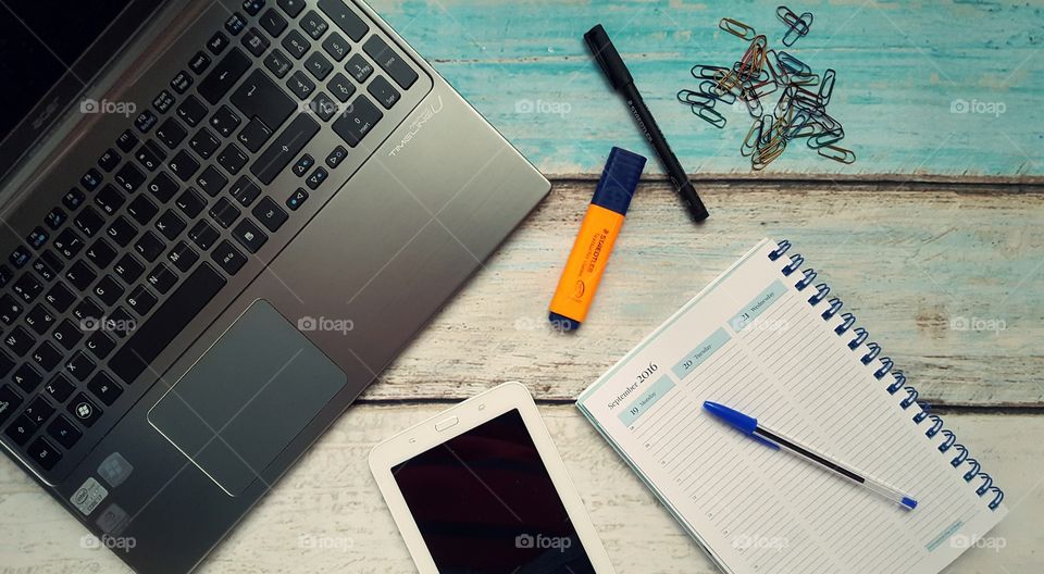 Desk with laptop, tablet, diary and markers