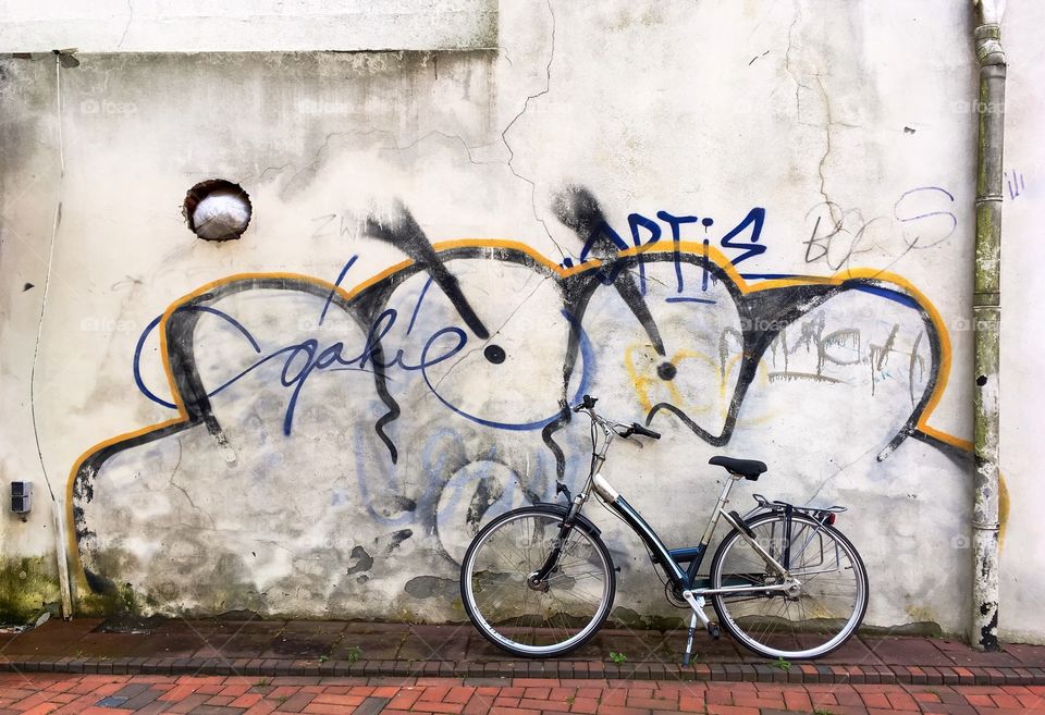 Bicycle leaning against cracked wall with graffiti in the street, Hilversum, Netherlands.