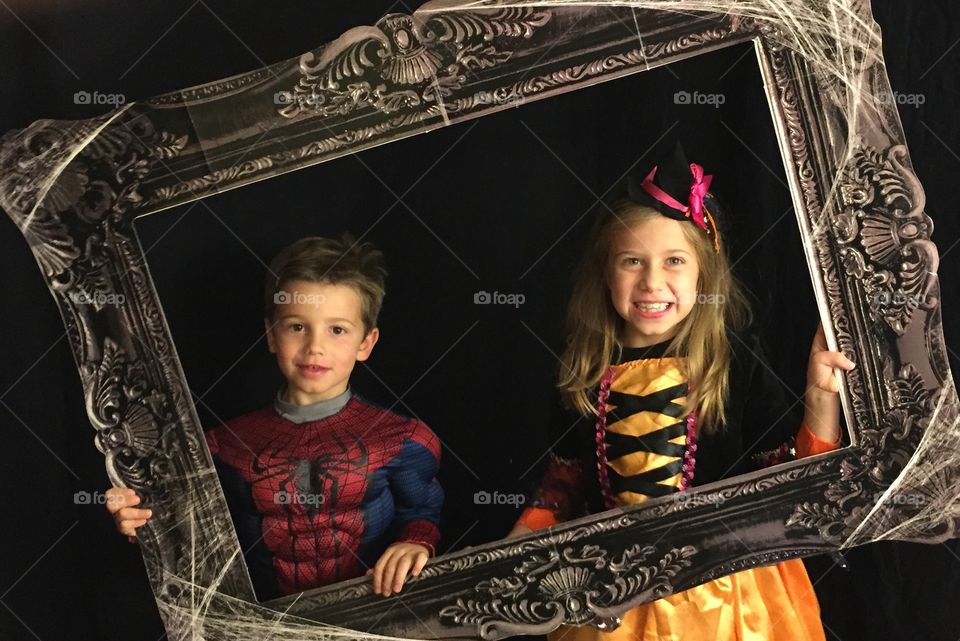 Brother and sister wearing costume looking through empty frame