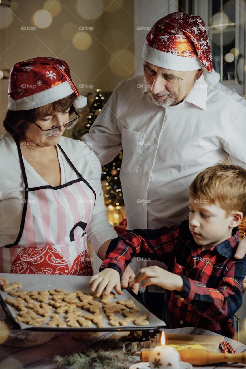 red-haired cute child boy with grandparents bakes cookies at home in the kitchen in kakun christmas