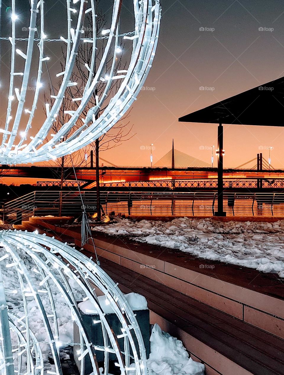 City scape in the evening. View of the bridge and river. Dominance of geometric shapes: triangle, rectangle, and circles. Winter landscape