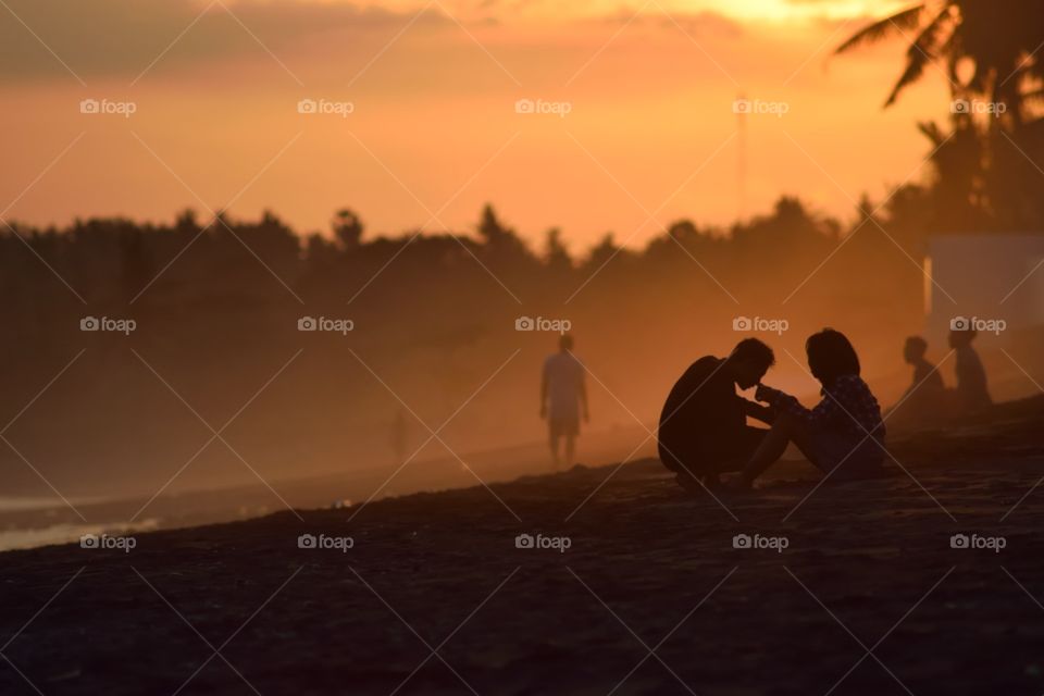 For lovers. Photo of a kissing couple at Keramas Beach, Bali showing them in front of an orange glowing sunset with fog/dust reflecting the light. One of my alltime favorites.