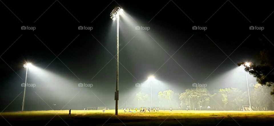 Stadium light tower reflectors against black background. Flood lighting for stadiums surround the circular turf ground. To provide proper illumination, high power high mast.