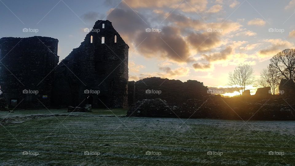 Ruined Abbey near Glenluce in southeast Scotland with frost in the foreground and a sunset in the background