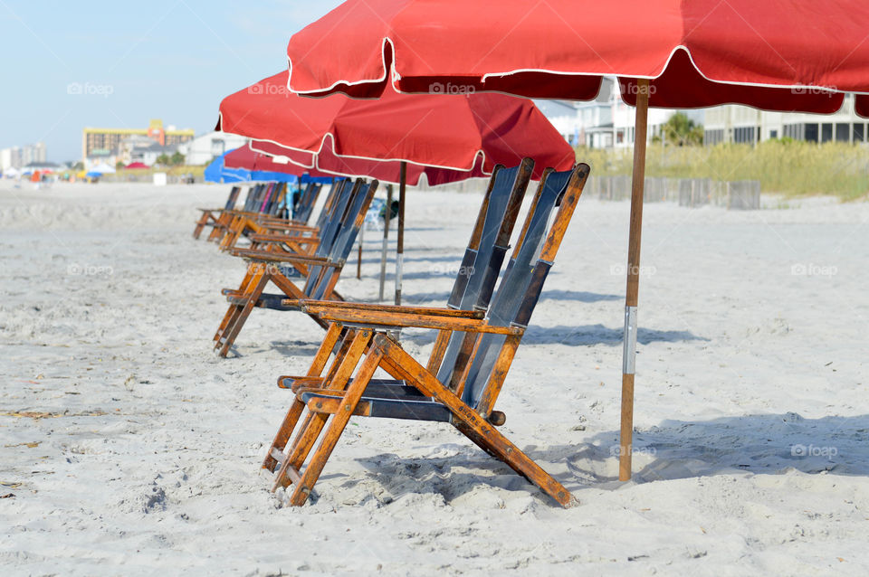 Row of lounge chairs and umbrellas set up on the beach with no people