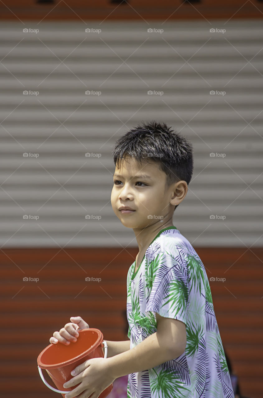 Asian boy holding Plastic bucket play Songkran festival or Thai new year in Thailand.