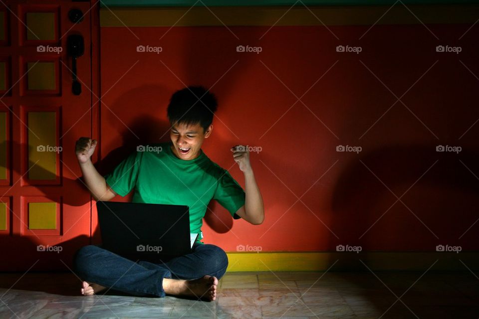 young asian teen with a laptop computer in a living room