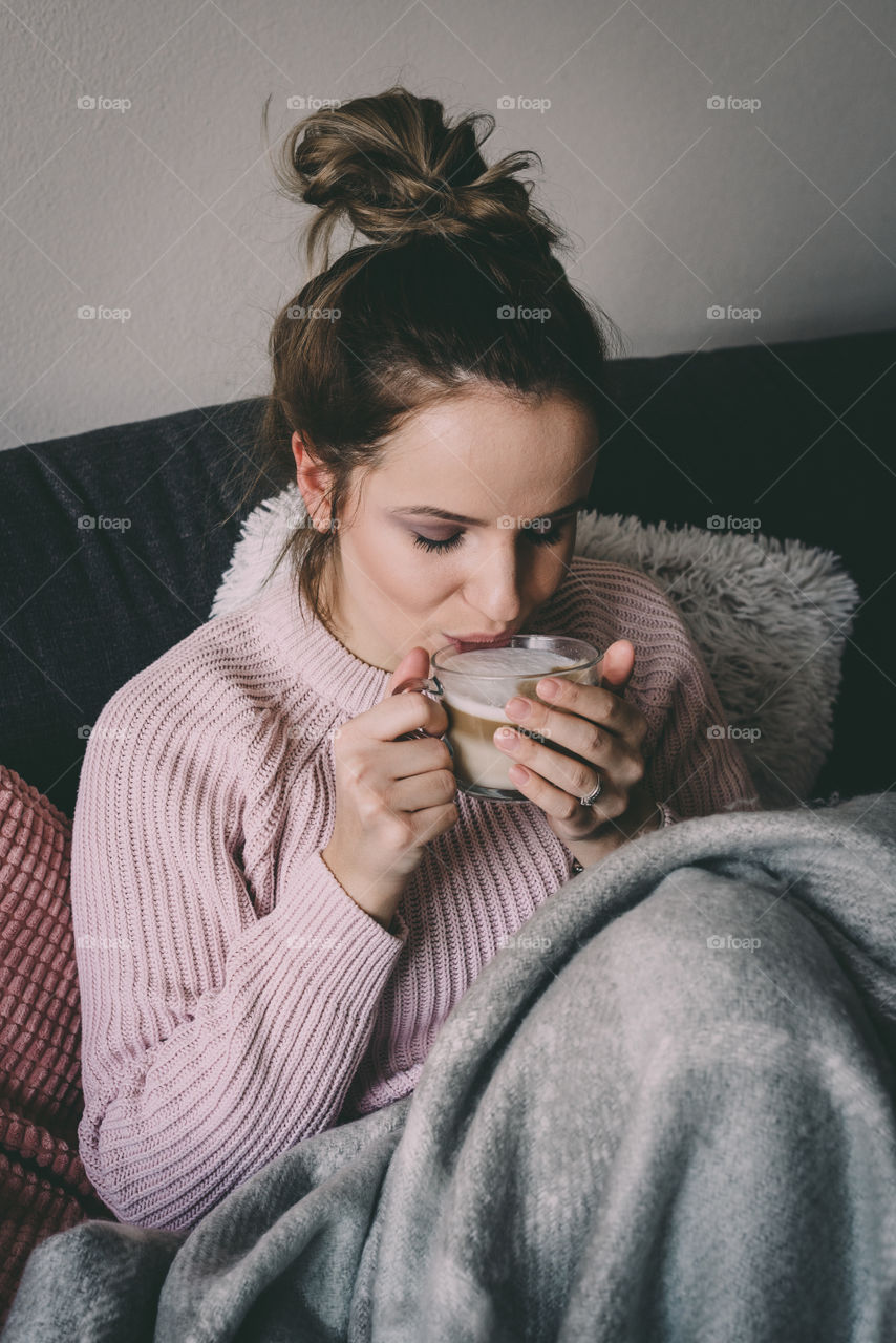 Hot coffee and a blanket. Woman relaxing at home. Cosy.