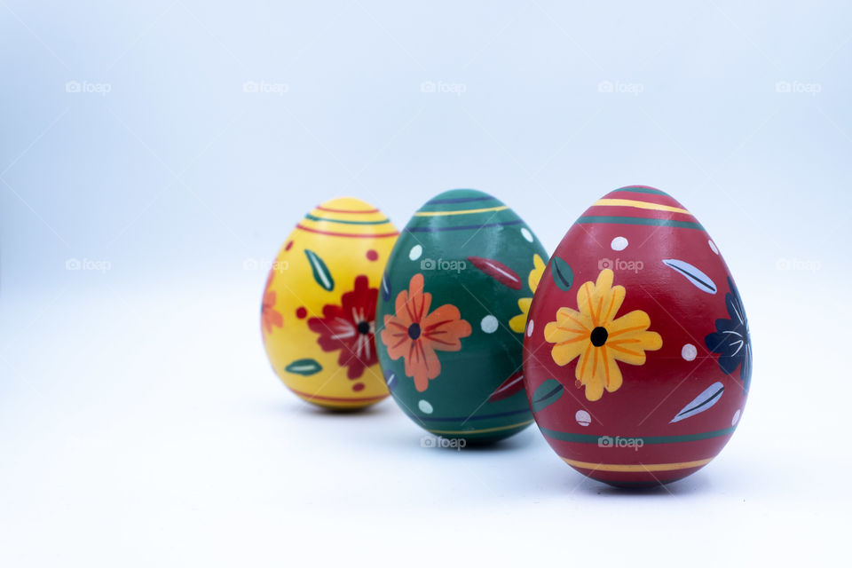 three wooden colorful easter eggs, with patterns, on white background