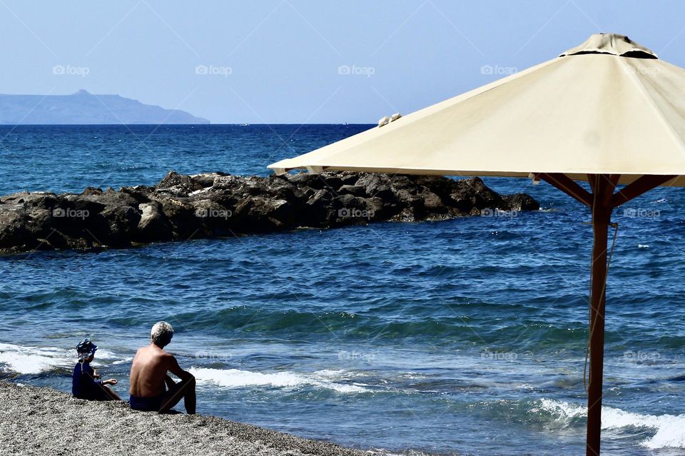 Father and son enjoying at peaceful beach at Agia Matina, Crete