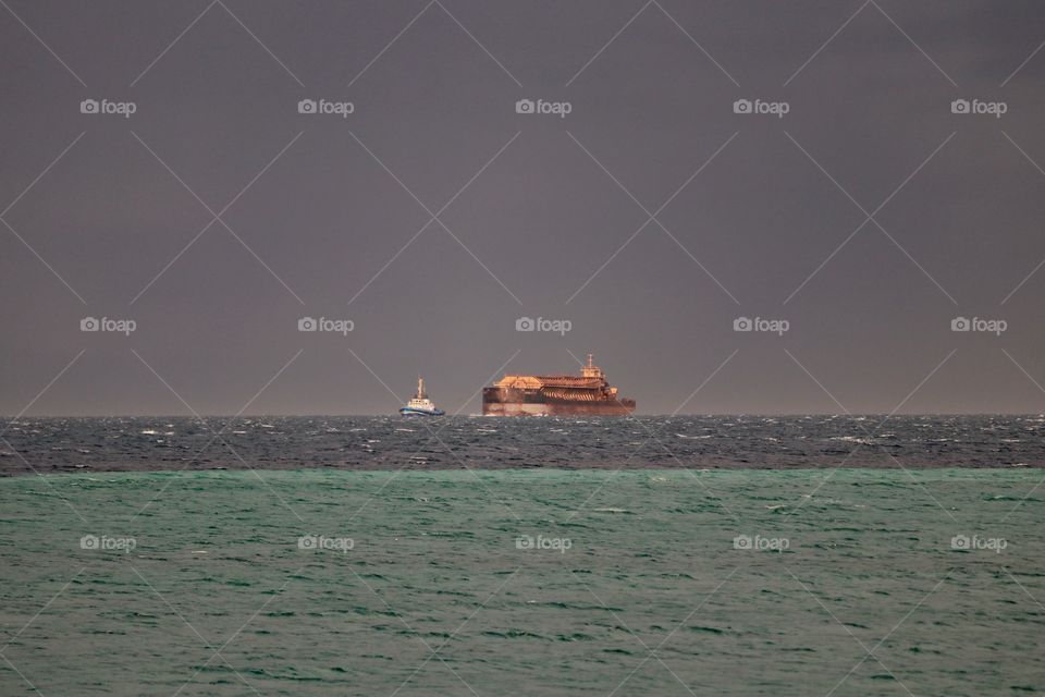 Tug boat tugging cargo ship in storm