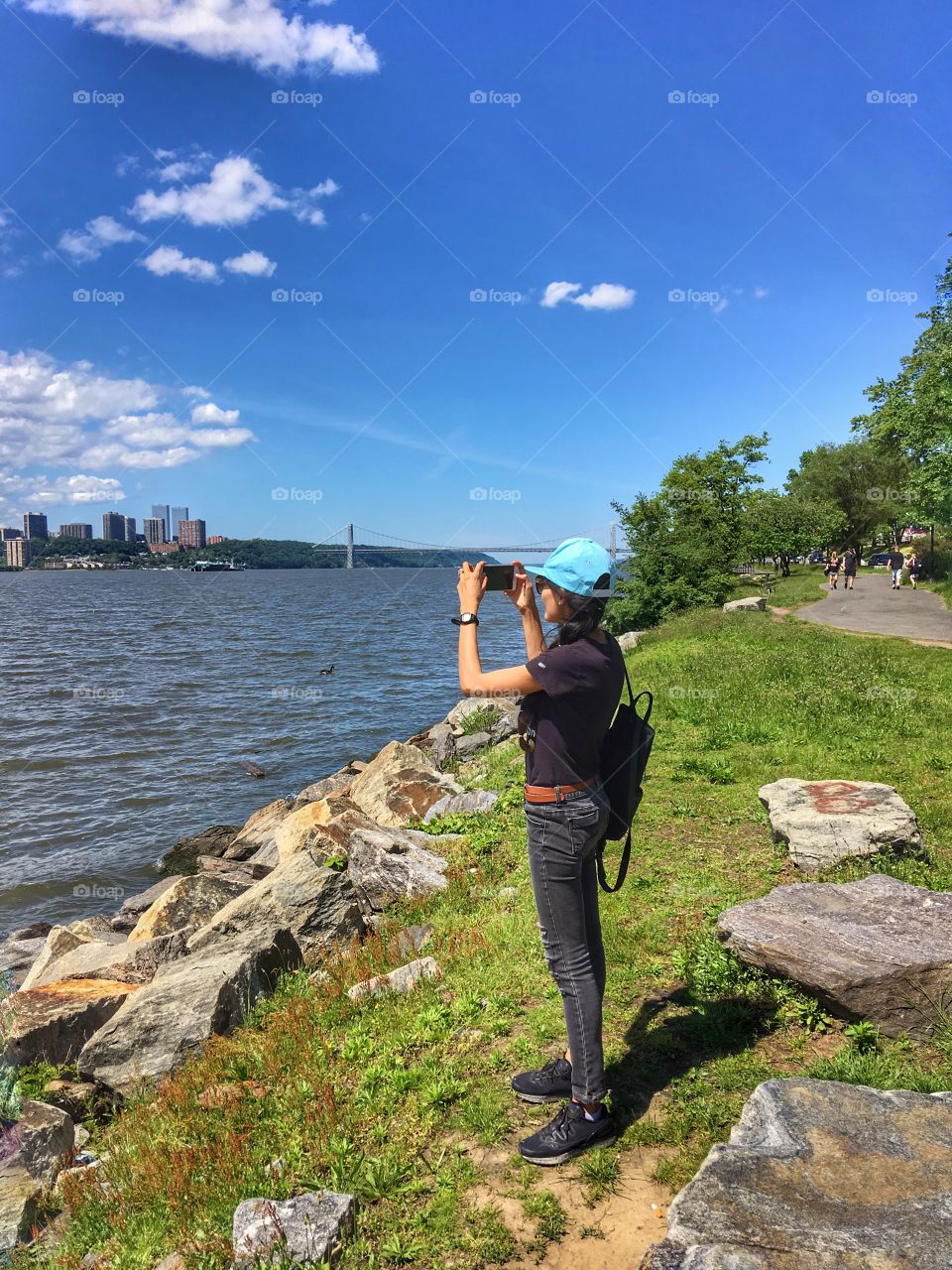 A woman standing at Riverside park, taking picture of New Jersey, USA. Sunny day.