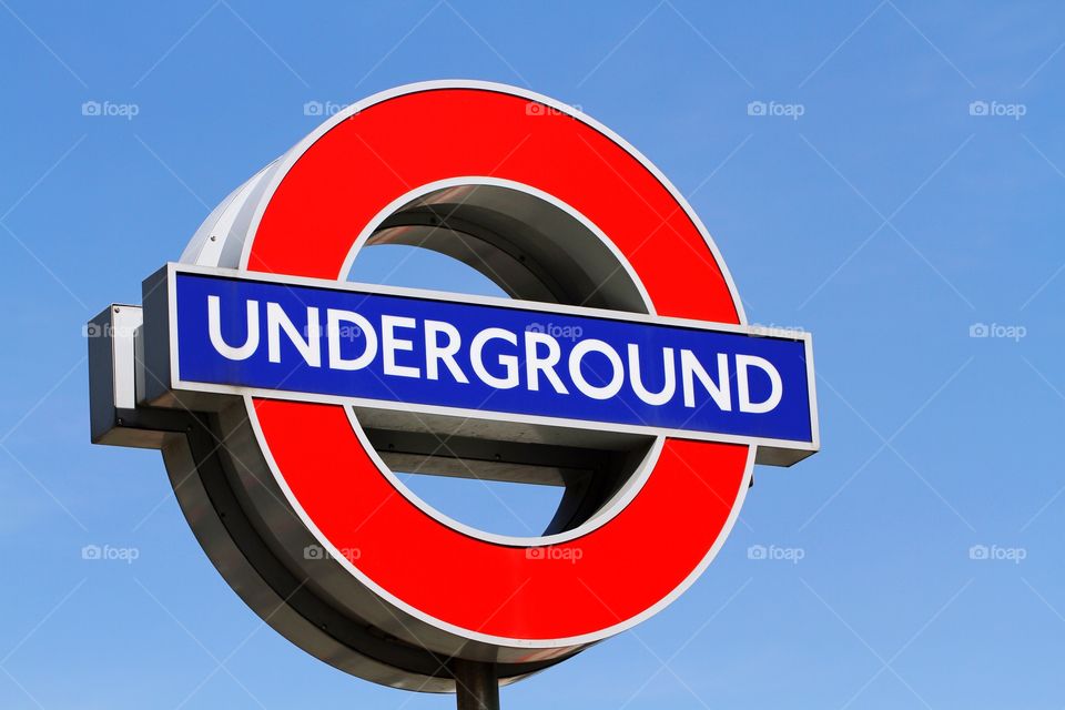 A colourful London Underground sign with a clear blue sky behind.