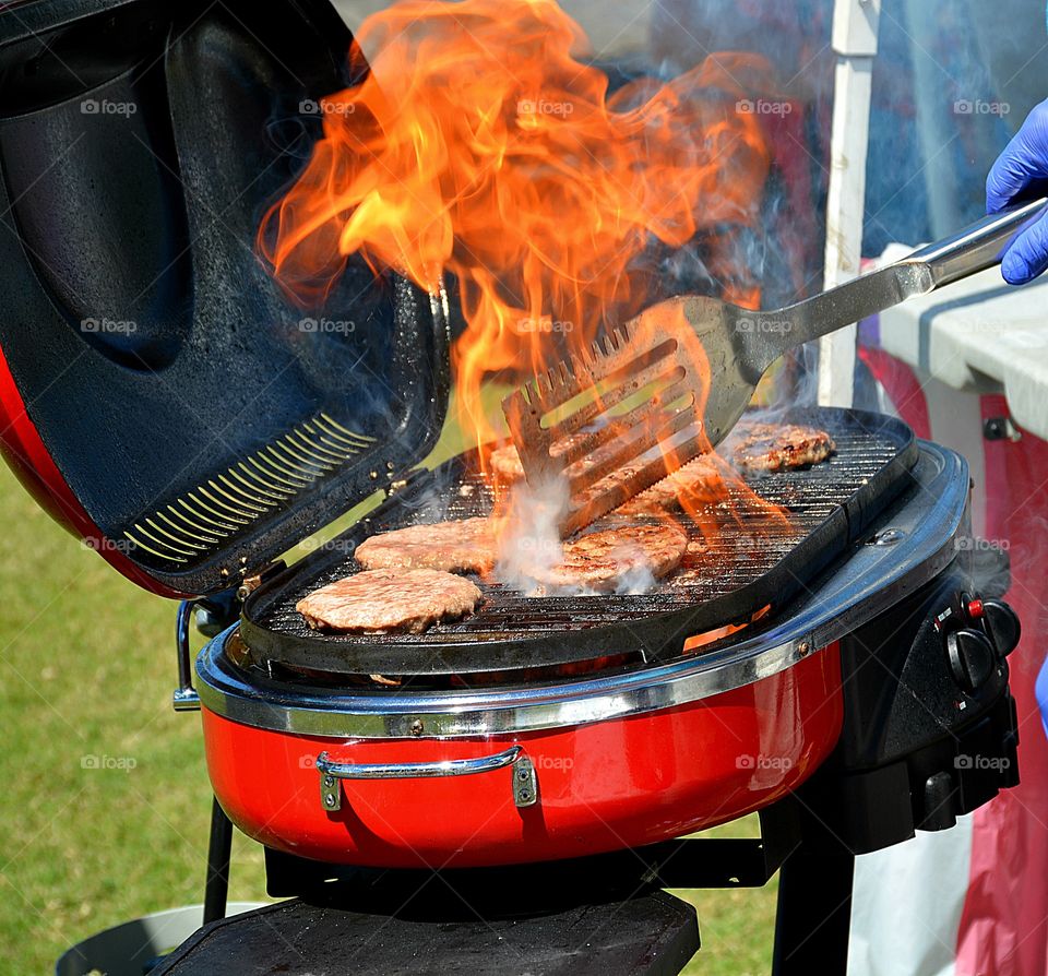 Moments freezed in photos. Flames shoot high in the air while cooking hamburgers on the gas grill. Amoment in time that you want to freeze for a lifetime