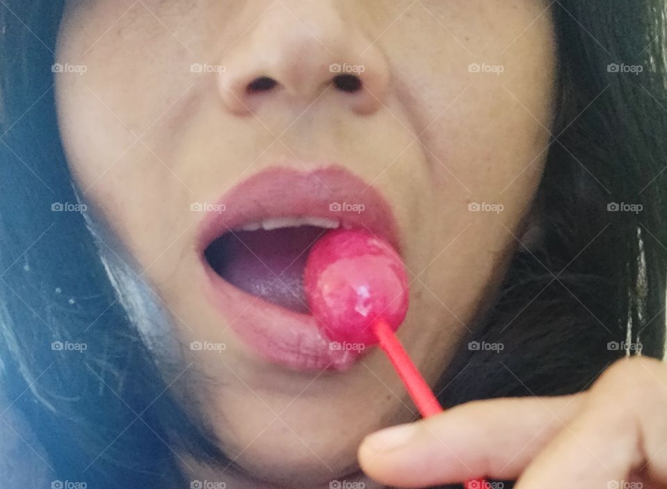 woman licking enjoying  a pink colored lollipop 😍