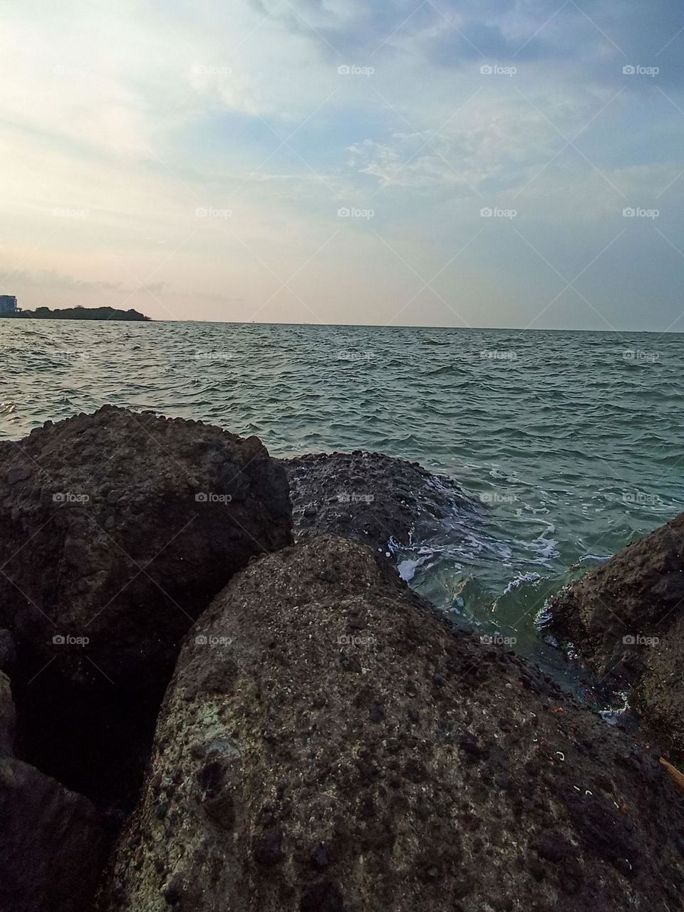 Coral rocks separate the ocean from land with a thin cloudy sky in eye angle view