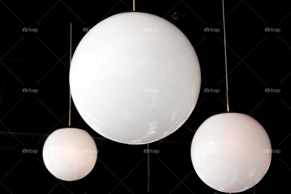 White round lamps hanging from the ceiling, black background 