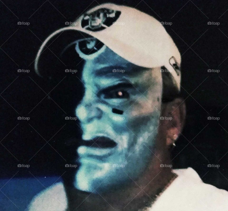 Raiders fan-- painted face, hat, scowling expression, tough look