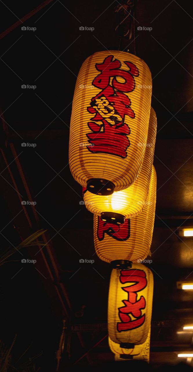 Traditional Japanese restaurant multiple yellow paper lantern outside hanging in the ceiling as decoration.