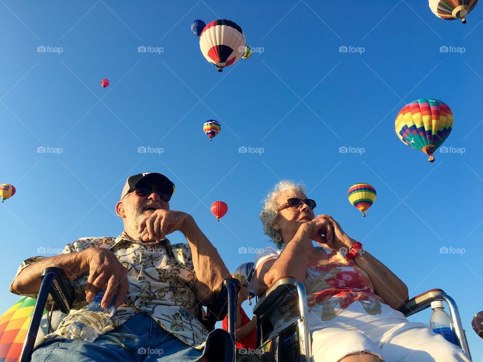 Happy senior couple with hot air balloon flying in clear sky
